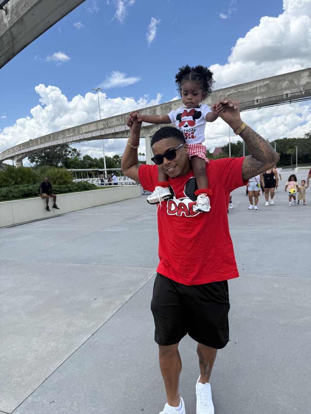 Brandon carrying his young daughter on his shoulders on a sunny day
