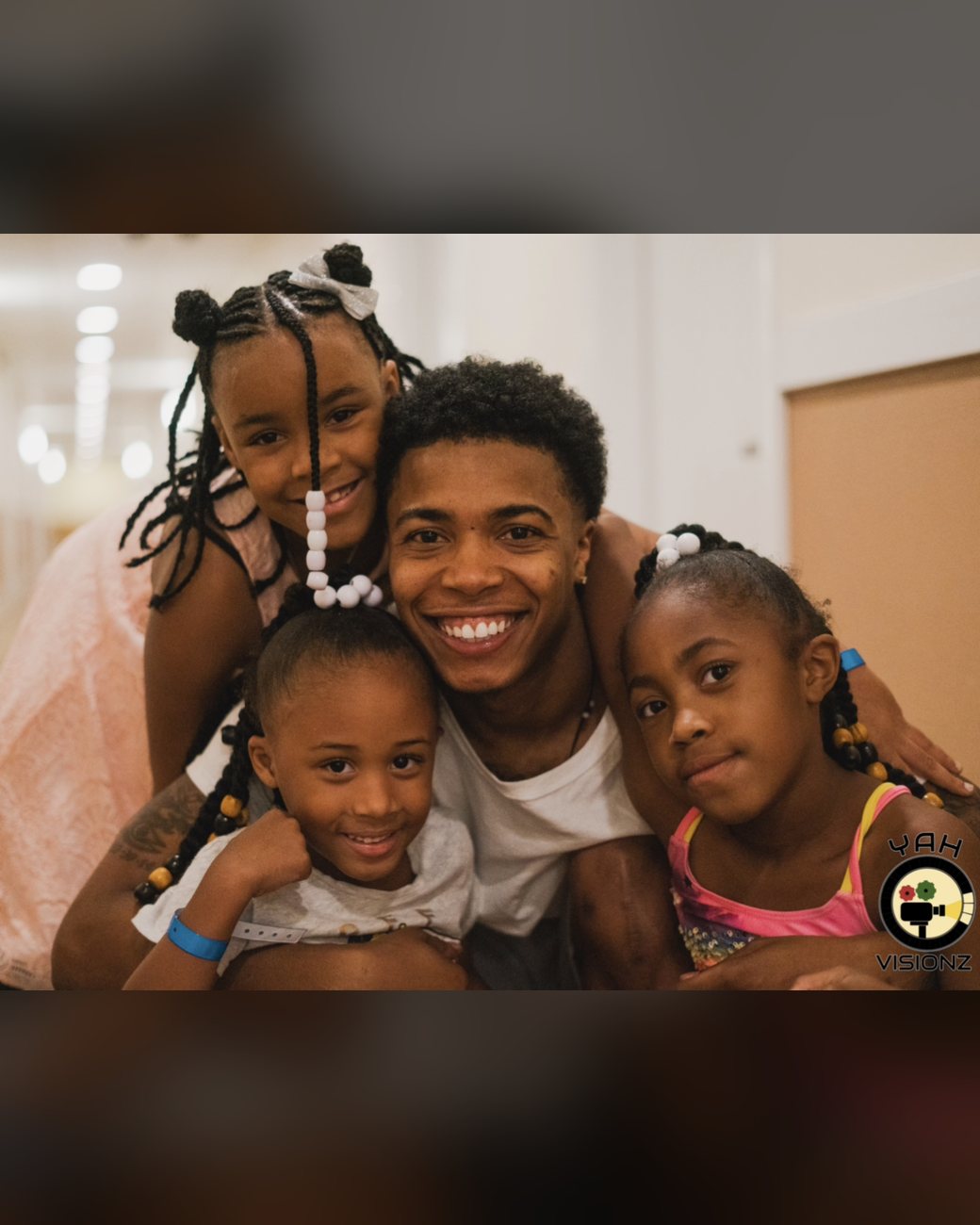Brandon smiling with three young girls in his arms