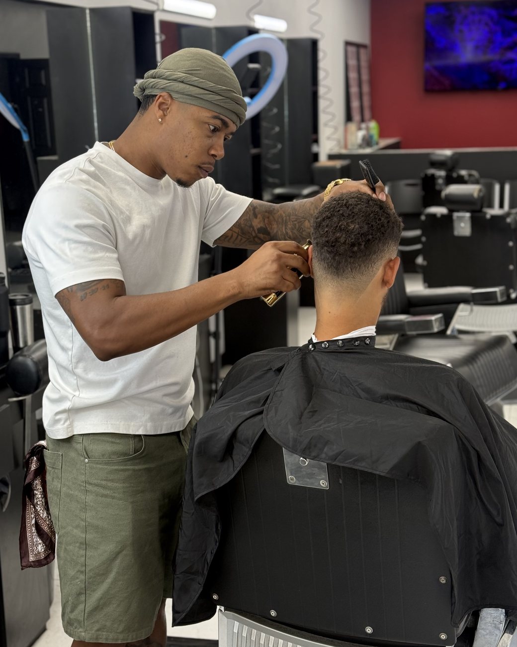 Brandon Payne cutting a taper fade at Fadeology Barbershop, gold clippers in hand